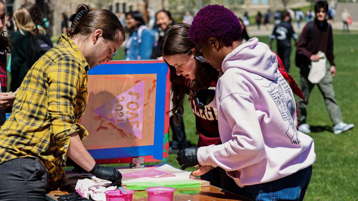 Three individuals collaborating on a screen-printing project for screen printing for social change event